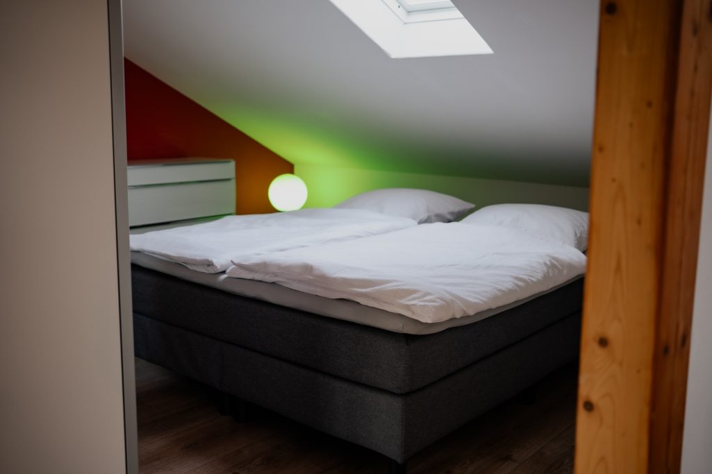 Helle Dachzimmer mit Doppelbett, bunten Wänden und einem skandinavischen Stil.