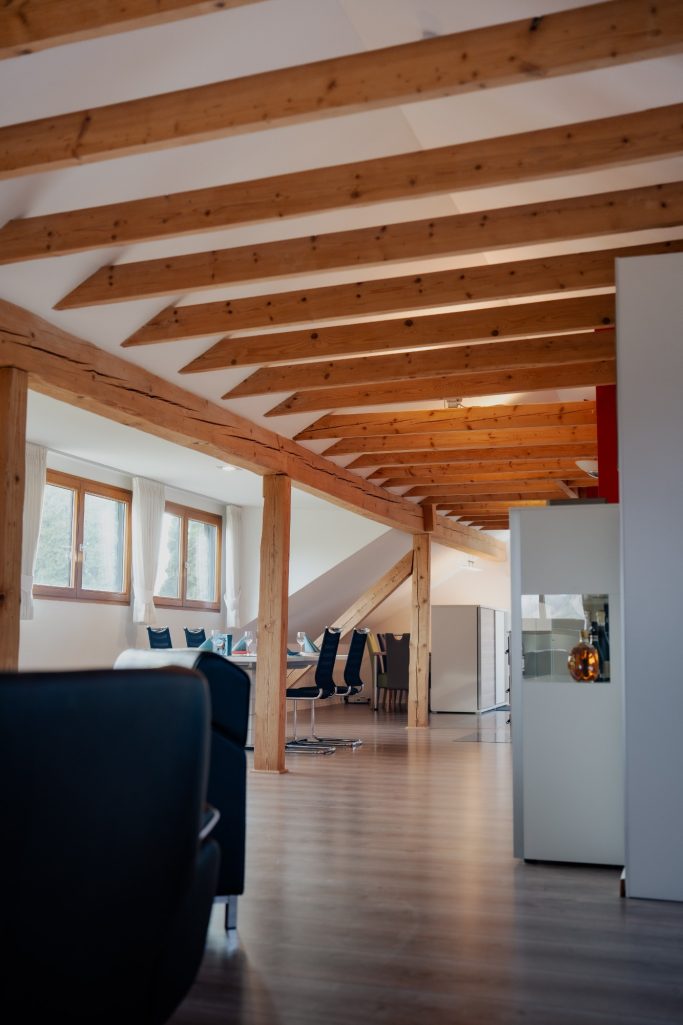 Heller Wohnraum mit Holzdecke, Sofa und Blick auf einen Essbereich.