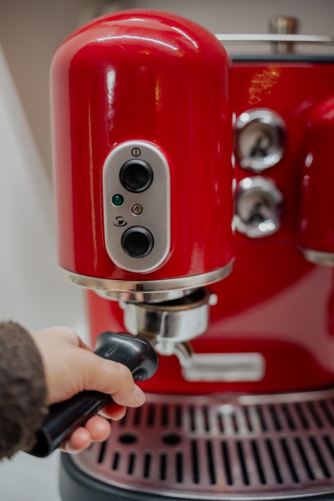 Rote Espressomaschine mit einem Handgriff zum Befestigen des Siebträgers.
