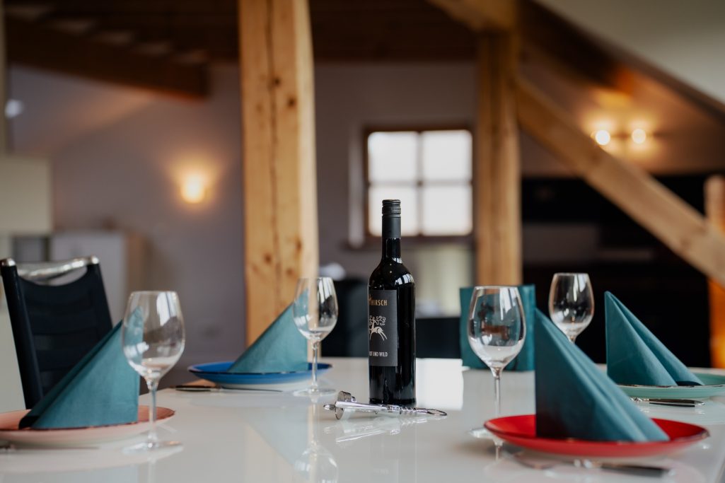 Elegant gedeckter Tisch mit Weinglas, schwarzer Flasche und bunten Servietten.