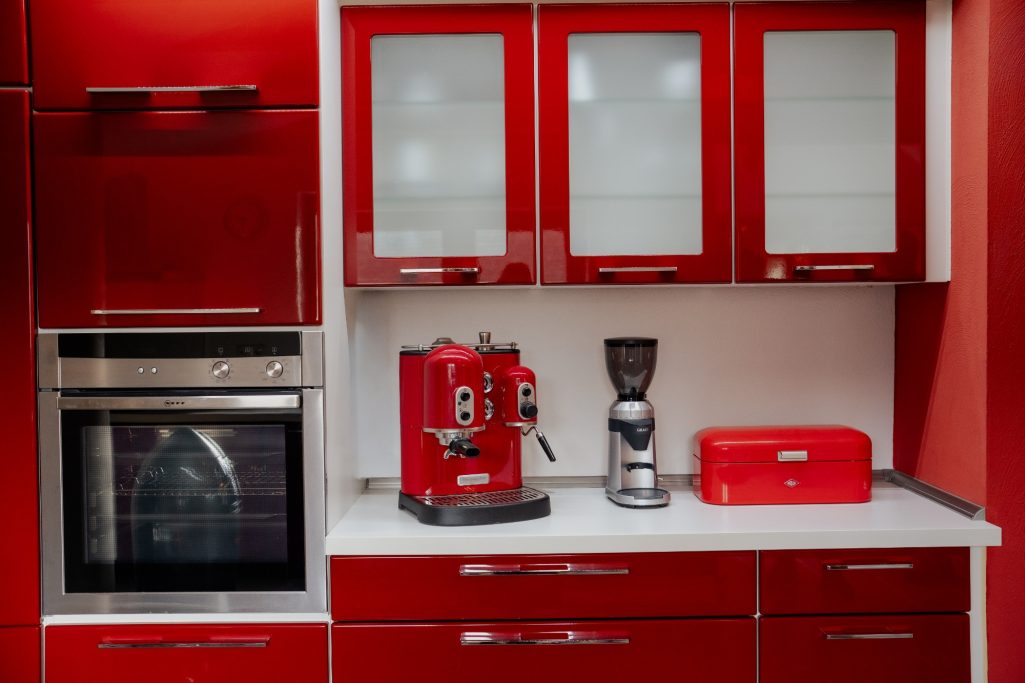 Moderne rot-weiße Küche mit Espressomaschine und Kaffeemühle auf einer Arbeitsfläche.